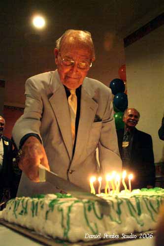 John cuts a cake at his 100th birthday party.